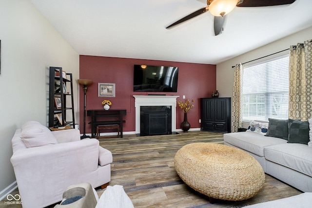 living room with a fireplace with flush hearth, a ceiling fan, baseboards, and wood finished floors