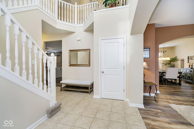 foyer entrance with arched walkways, a high ceiling, wood finished floors, baseboards, and stairs