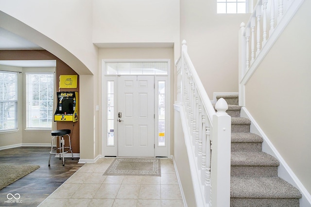 tiled entryway with stairway, a towering ceiling, and baseboards