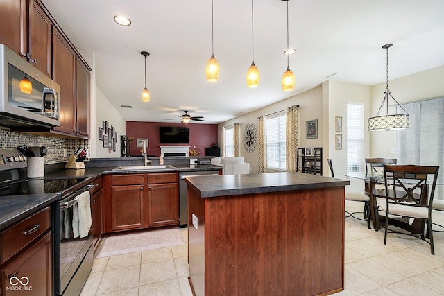 kitchen featuring stainless steel appliances, dark countertops, backsplash, open floor plan, and a sink