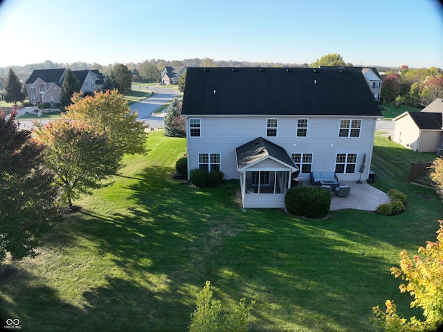 rear view of property featuring a sunroom, a patio area, and a yard