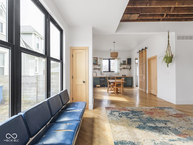 living room with a barn door, wood finished floors, visible vents, and baseboards