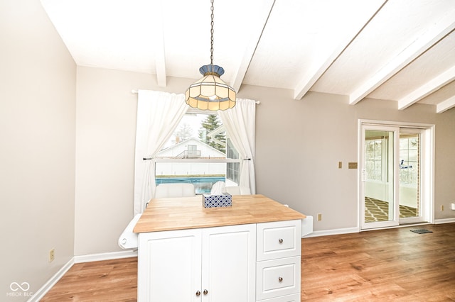 unfurnished dining area with light wood-style floors, baseboards, and beamed ceiling