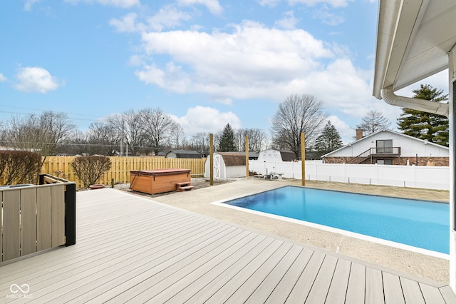 view of pool with a hot tub, an outdoor structure, a fenced backyard, and a shed