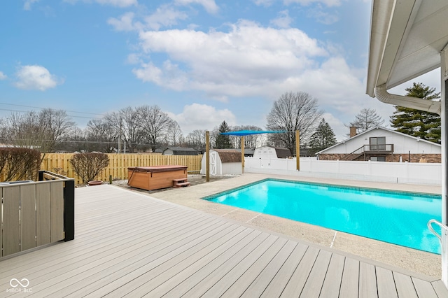 view of swimming pool with a hot tub, a fenced in pool, a fenced backyard, a deck, and a shed