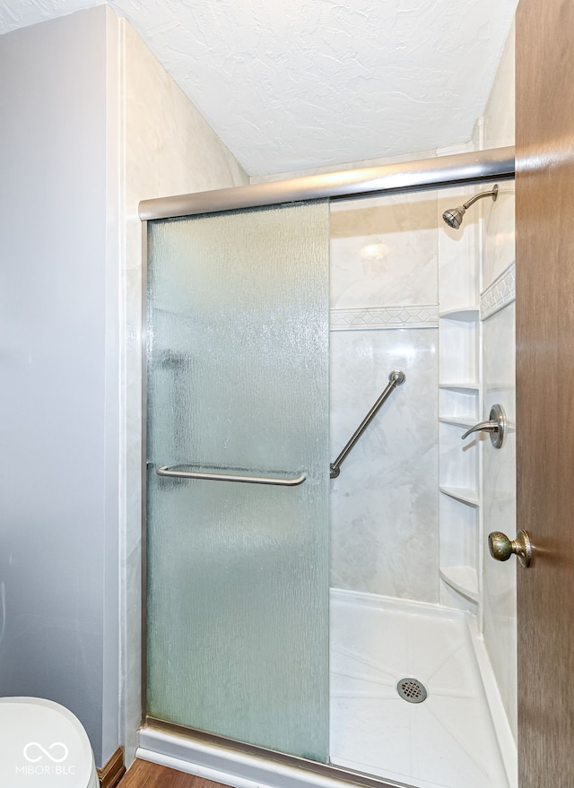 bathroom with a stall shower, a textured ceiling, and toilet