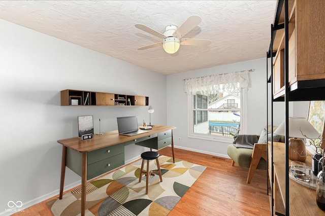 office with light wood-style floors, visible vents, baseboards, and a textured ceiling