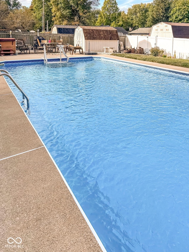 view of swimming pool with an outbuilding, a fenced backyard, a fenced in pool, a storage unit, and a patio area