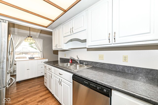 kitchen with stainless steel appliances, dark countertops, white cabinetry, a sink, and wood finished floors