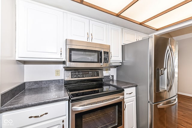 kitchen with wood finished floors, baseboards, white cabinets, appliances with stainless steel finishes, and dark countertops