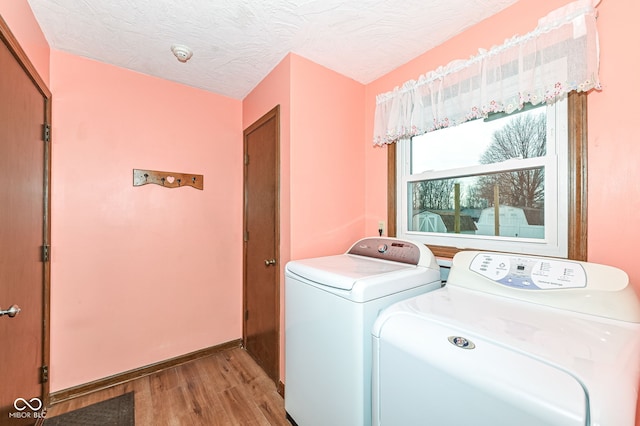 washroom with a textured ceiling, laundry area, wood finished floors, and washing machine and clothes dryer