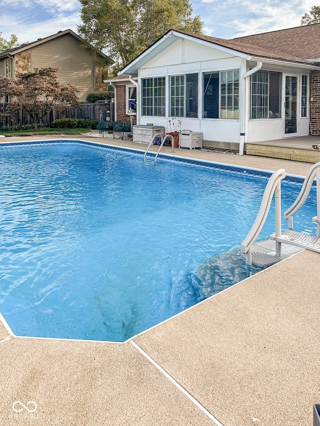 view of swimming pool with a sunroom, a patio area, fence, and a fenced in pool