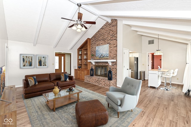 living area with a fireplace, visible vents, baseboards, light wood-style floors, and beam ceiling