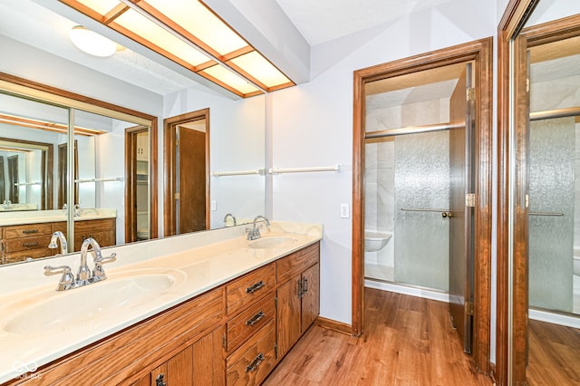 full bathroom featuring double vanity, wood finished floors, a sink, and toilet