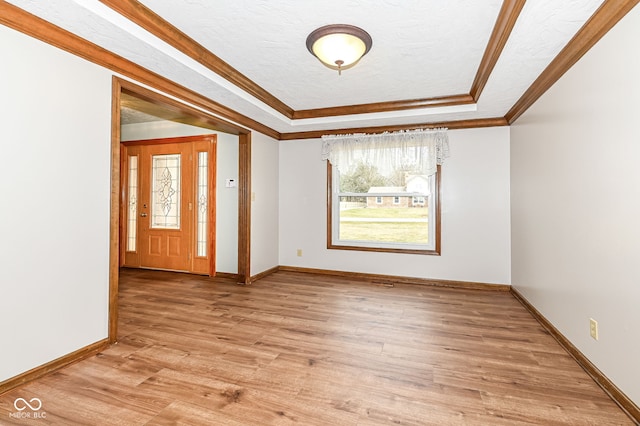 entryway featuring light wood-style floors, a raised ceiling, crown molding, and baseboards