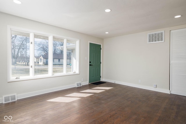 unfurnished room with baseboards, visible vents, and dark wood-type flooring