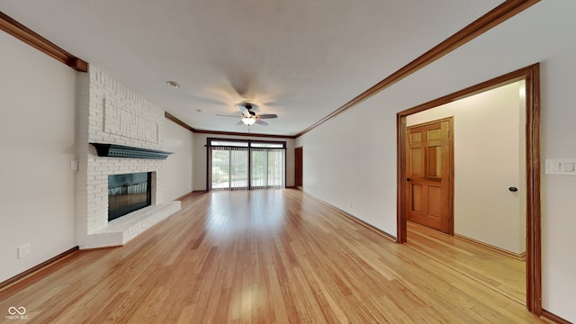 unfurnished living room with a ceiling fan, a textured ceiling, crown molding, light wood-type flooring, and a brick fireplace