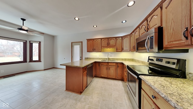 kitchen featuring visible vents, appliances with stainless steel finishes, a peninsula, light stone countertops, and a sink