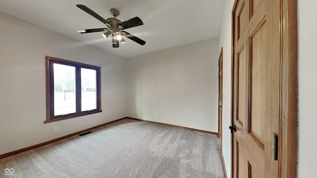 unfurnished room with a ceiling fan, visible vents, light carpet, and baseboards