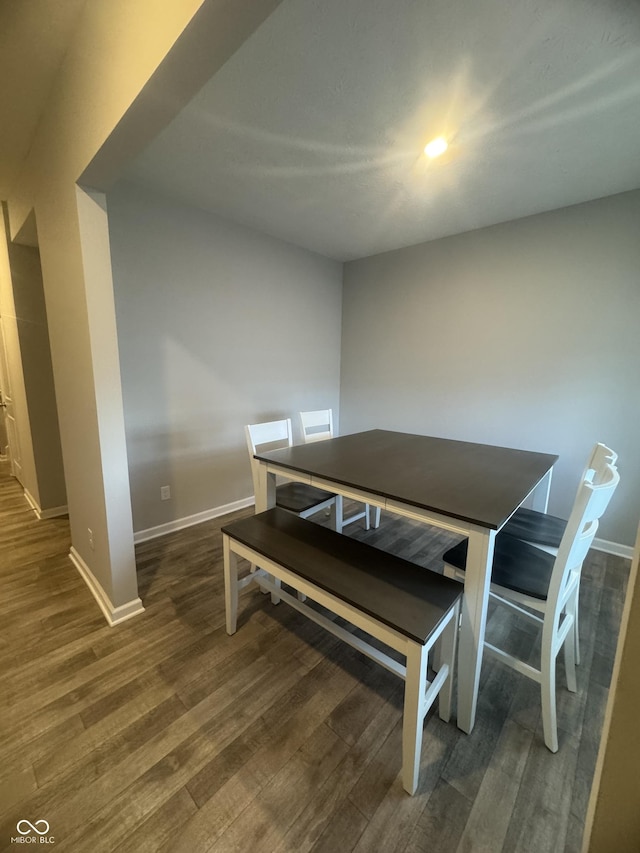 dining space with baseboards and wood finished floors