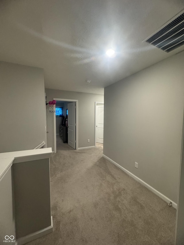 spare room featuring carpet, visible vents, and baseboards