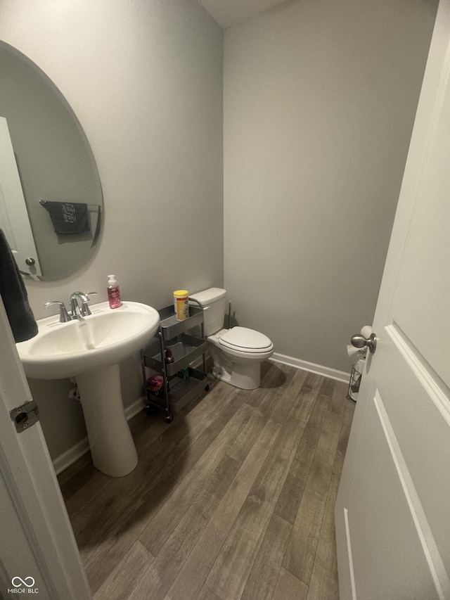 bathroom featuring baseboards, toilet, and wood finished floors