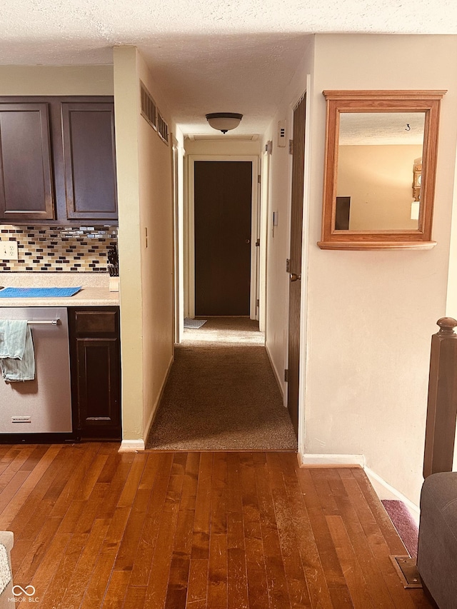 hall featuring baseboards, dark wood finished floors, and a textured ceiling