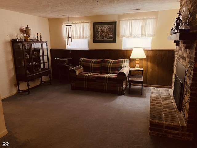 carpeted living room with a textured ceiling, wood walls, a wainscoted wall, and a brick fireplace