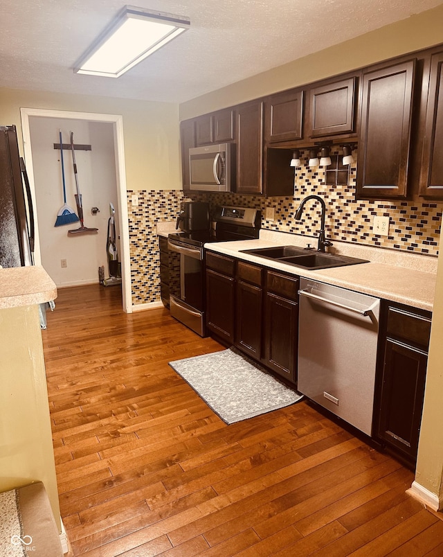 kitchen with stainless steel appliances, hardwood / wood-style floors, a sink, and light countertops