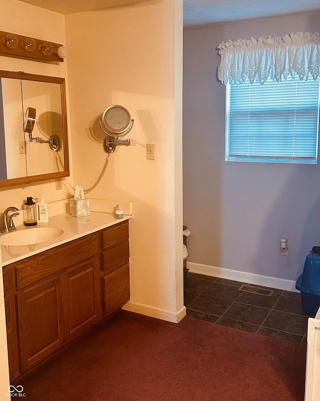 bathroom featuring visible vents, vanity, baseboards, and tile patterned floors