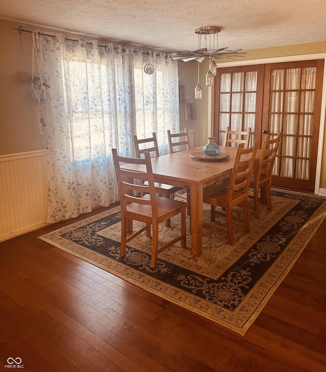 dining area featuring a textured ceiling, hardwood / wood-style floors, wainscoting, and plenty of natural light