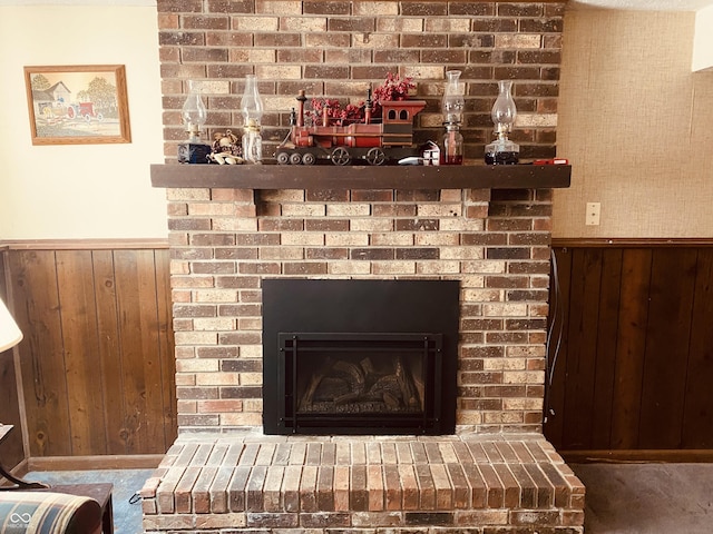 interior details with a wainscoted wall, wood walls, a brick fireplace, and carpet flooring