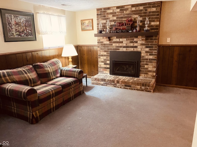 carpeted living area featuring a textured ceiling, wood walls, wainscoting, and a fireplace