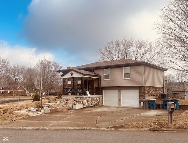 split level home with brick siding, a chimney, central AC, a garage, and driveway