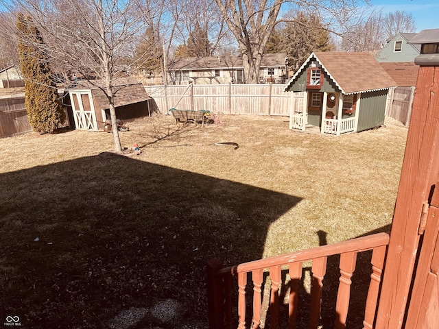 view of yard featuring an outbuilding, a fenced backyard, and a storage unit