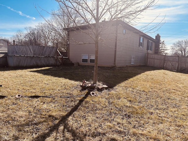 view of side of home with a yard and fence