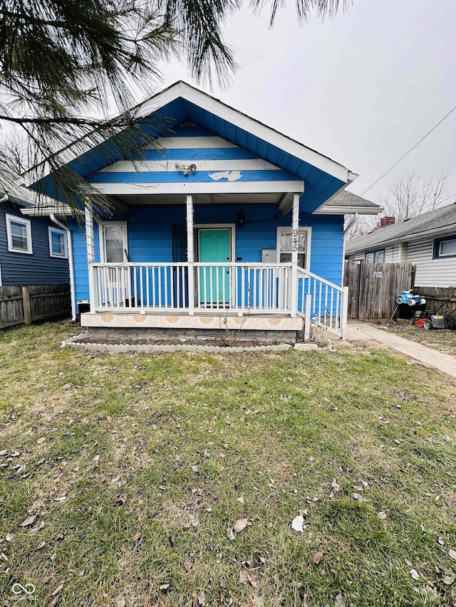 bungalow-style house with a front yard, covered porch, and fence