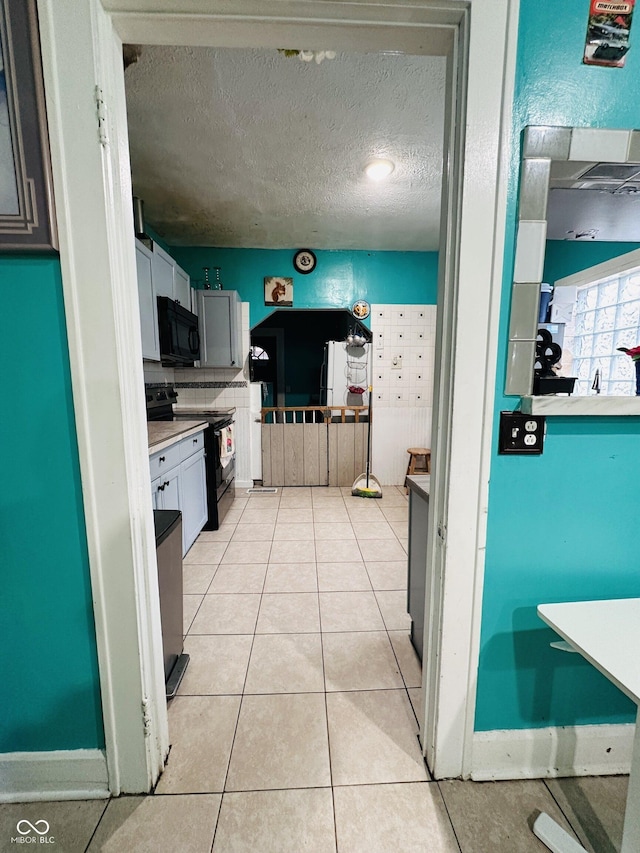 kitchen featuring black appliances, light countertops, a textured ceiling, and light tile patterned flooring