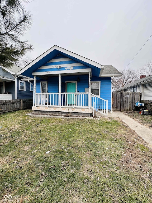 bungalow-style home featuring a porch, a front lawn, and fence