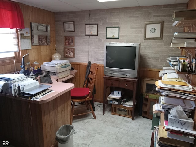 home office featuring light tile patterned floors, a paneled ceiling, and wooden walls