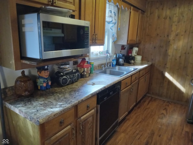 kitchen with black dishwasher, stainless steel microwave, a sink, wooden walls, and wood finished floors