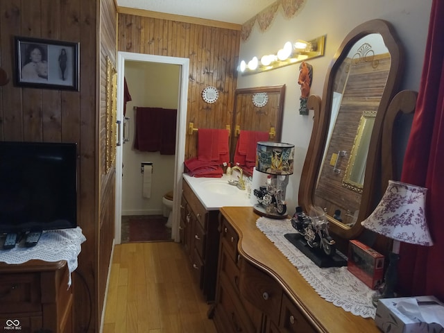 bathroom with toilet, wood walls, wood finished floors, and vanity