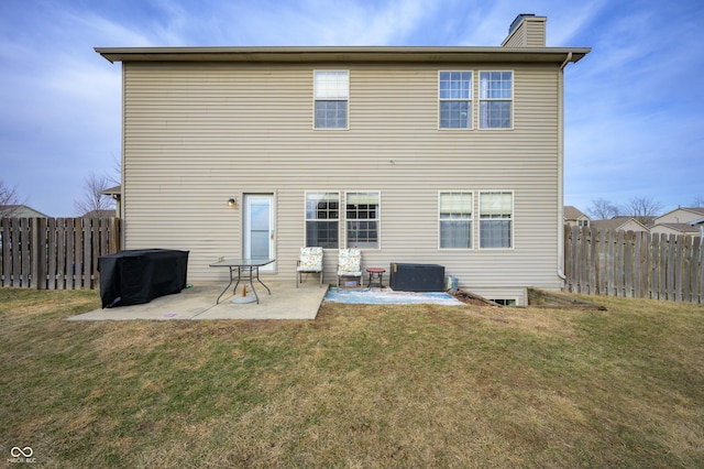 rear view of property with a yard, a fenced backyard, a chimney, and a patio