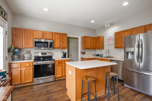 kitchen with a center island, light countertops, appliances with stainless steel finishes, dark wood-type flooring, and a sink