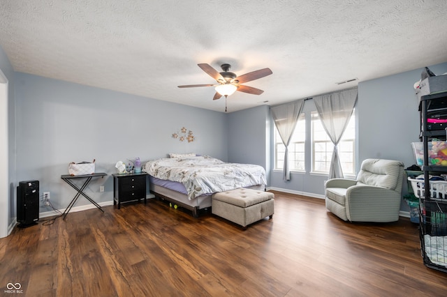 bedroom with dark wood-style floors, visible vents, a textured ceiling, and baseboards