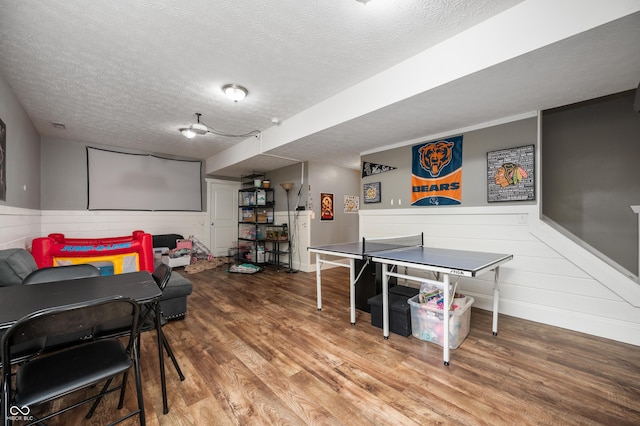 game room featuring wainscoting, a textured ceiling, and wood finished floors