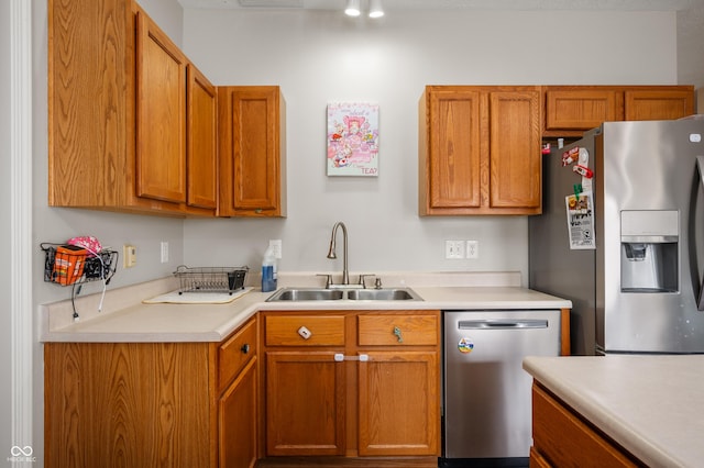 kitchen with stainless steel appliances, brown cabinets, light countertops, and a sink