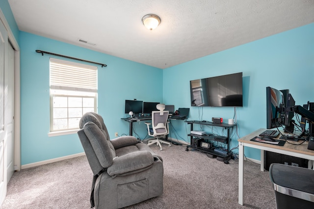 carpeted office space featuring baseboards, visible vents, and a textured ceiling