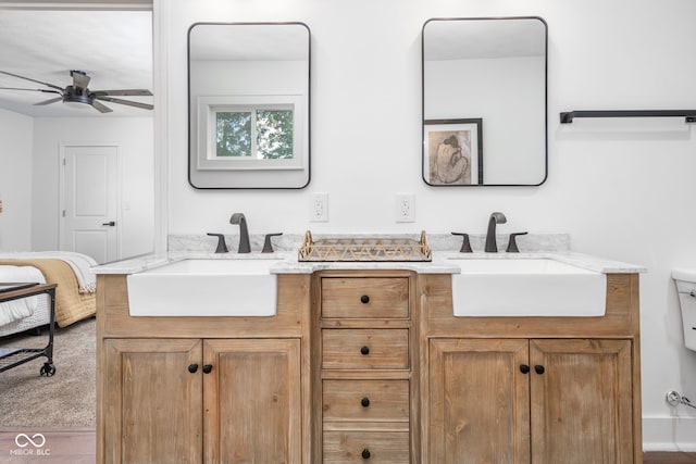 full bath featuring toilet, double vanity, a sink, and a ceiling fan