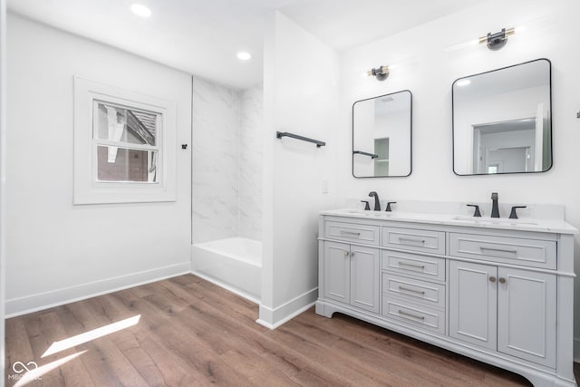 bathroom with double vanity, baseboards, a sink, and wood finished floors